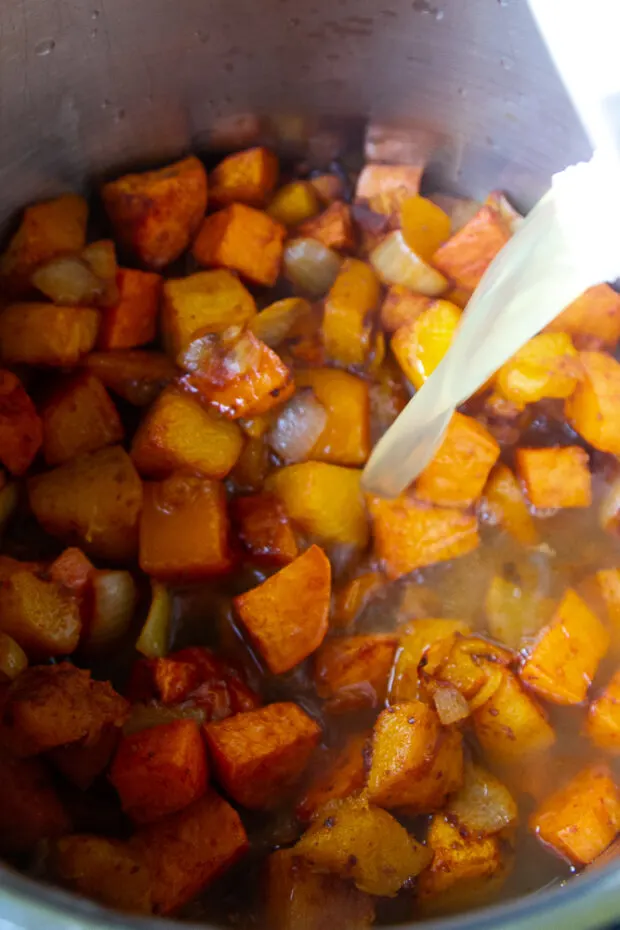 Roasted vegetables in a soup pot with chicken broth poured in.