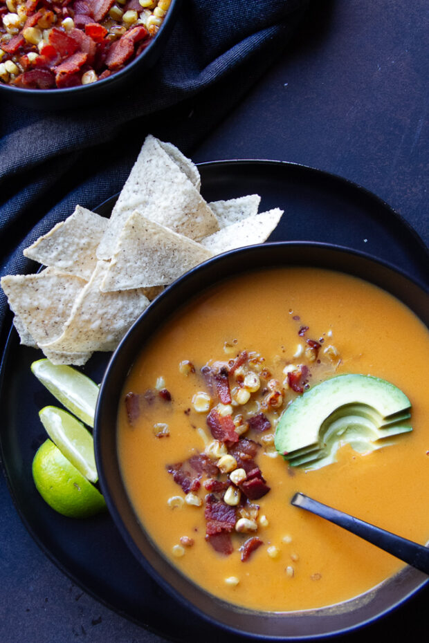 Black bowl with finished soup and garnishes.