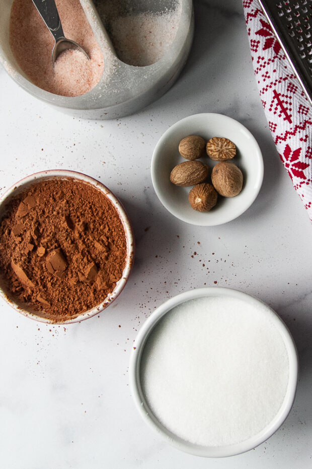 Ingredients set out to make this cinnamon sugar: Sugar, cinnamon, cocoa powder, nutmeg, and sea salt.