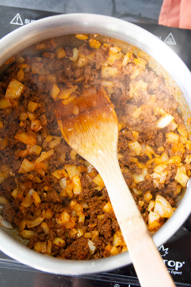 Chorizo and onions cooking in a pot.