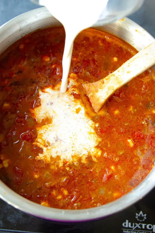 Adding heavy cream to the chili.