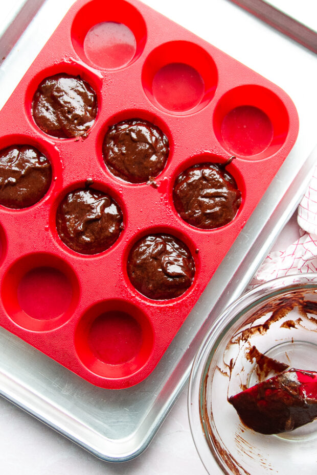 Chocolate batter spooned into a silicone muffin pan.