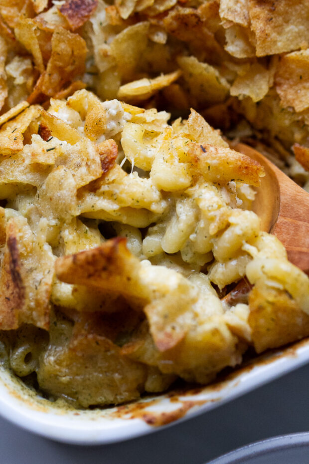 Close up of the tuna noodle casserole and the wooden spoon scooping pasta.