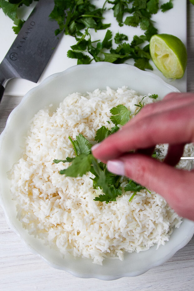 Adding fresh lime juice and fresh cilantro to cooked white rice.