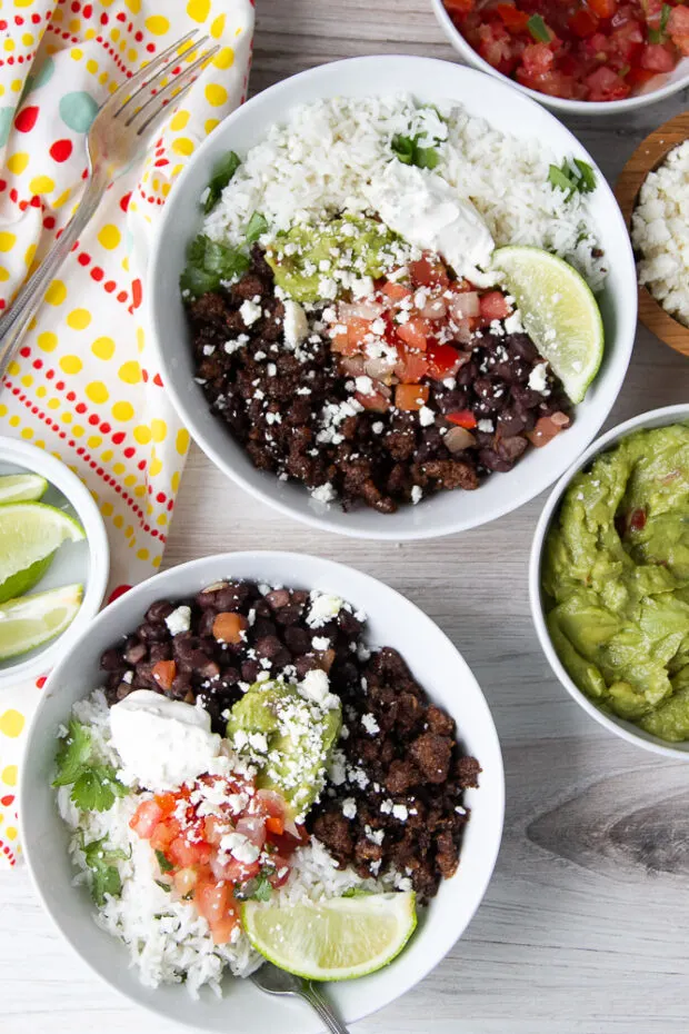 Two assembled burrito bowls in white bowls. 