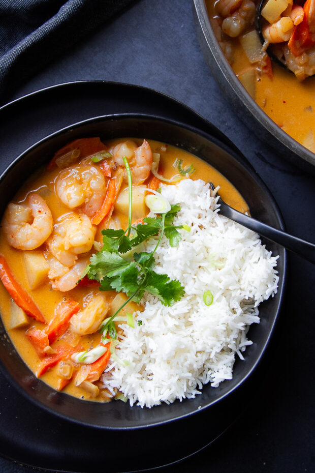 Coconut Shrimp Curry in a black bowl with jasmine rice.