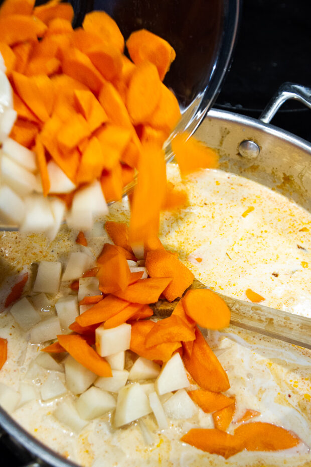 Adding carrots and potatoes to the skillet with the coconut milk.