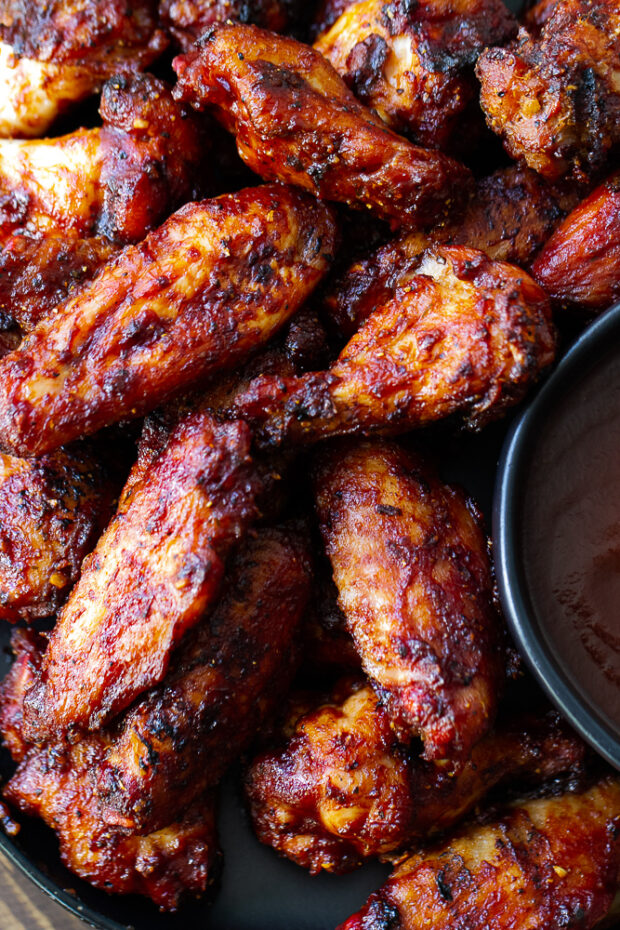 Smoked Chicken Wings on a plate with a small bowl of BBQ sauce.
