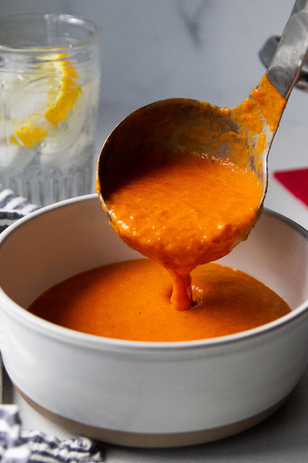 Ladling soup into a white bowl.