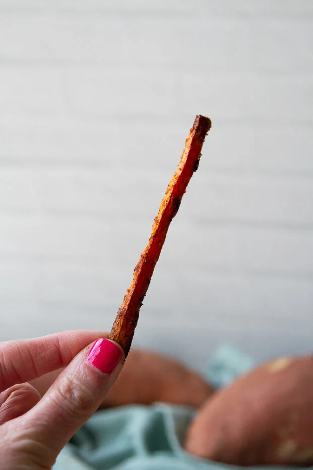 A single sweet potato fry held in a hand -- it's sticking straight up. Not soggy!