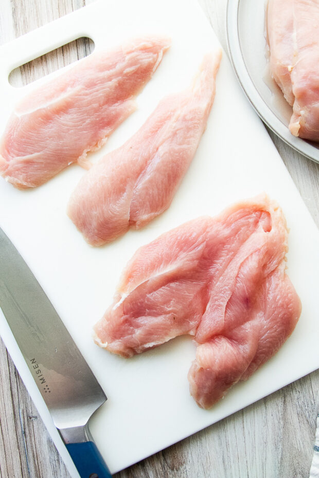 Chicken breast pieces being butterflied to create two thinner cutlets.