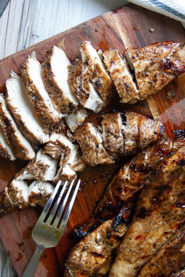 Sliced, freshly grilled balsamic chicken on a cutting board.