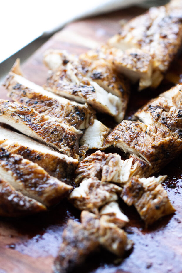 Sliced grilled balsamic chicken on a cutting board.