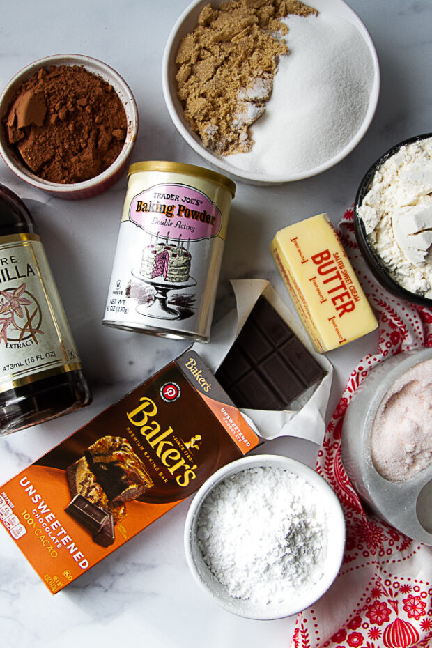 Ingredients for chocolate crinkle cookies: Unsweetened chocolate, cocoa powder, brown sugar, granulated sugar, baking powder, vanilla, butter, gluten free flour, powdered sugar, salt.