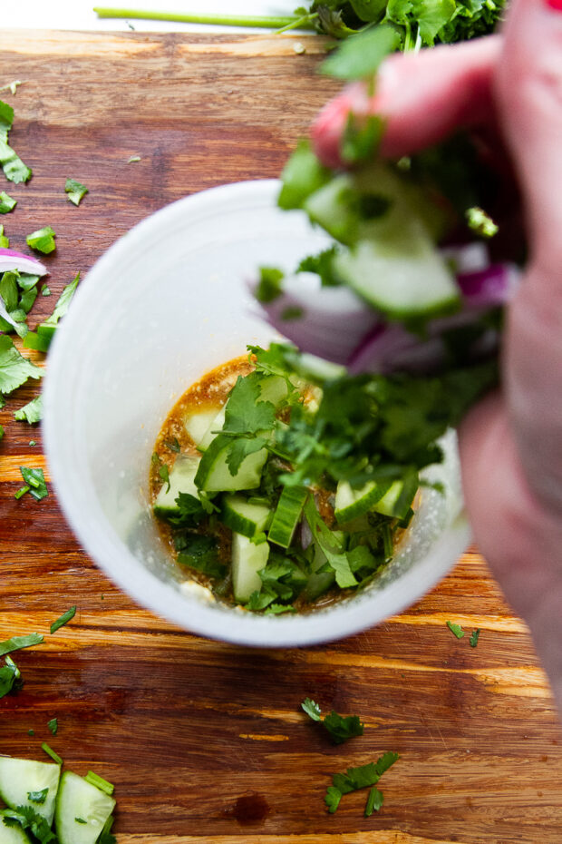 Chopped veg being added to the container with the dressing.
