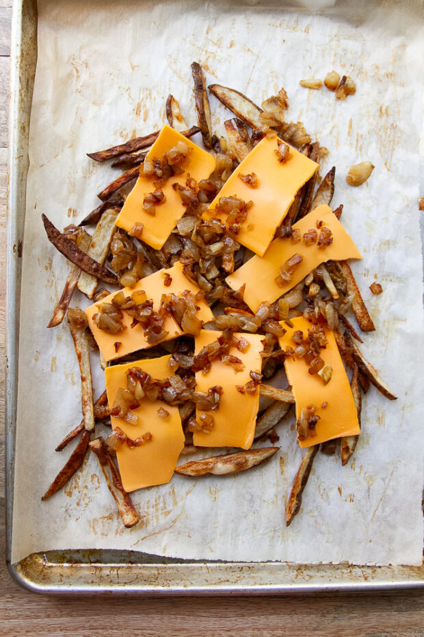 Cheese slices and caramelized onions on top of oven fries.